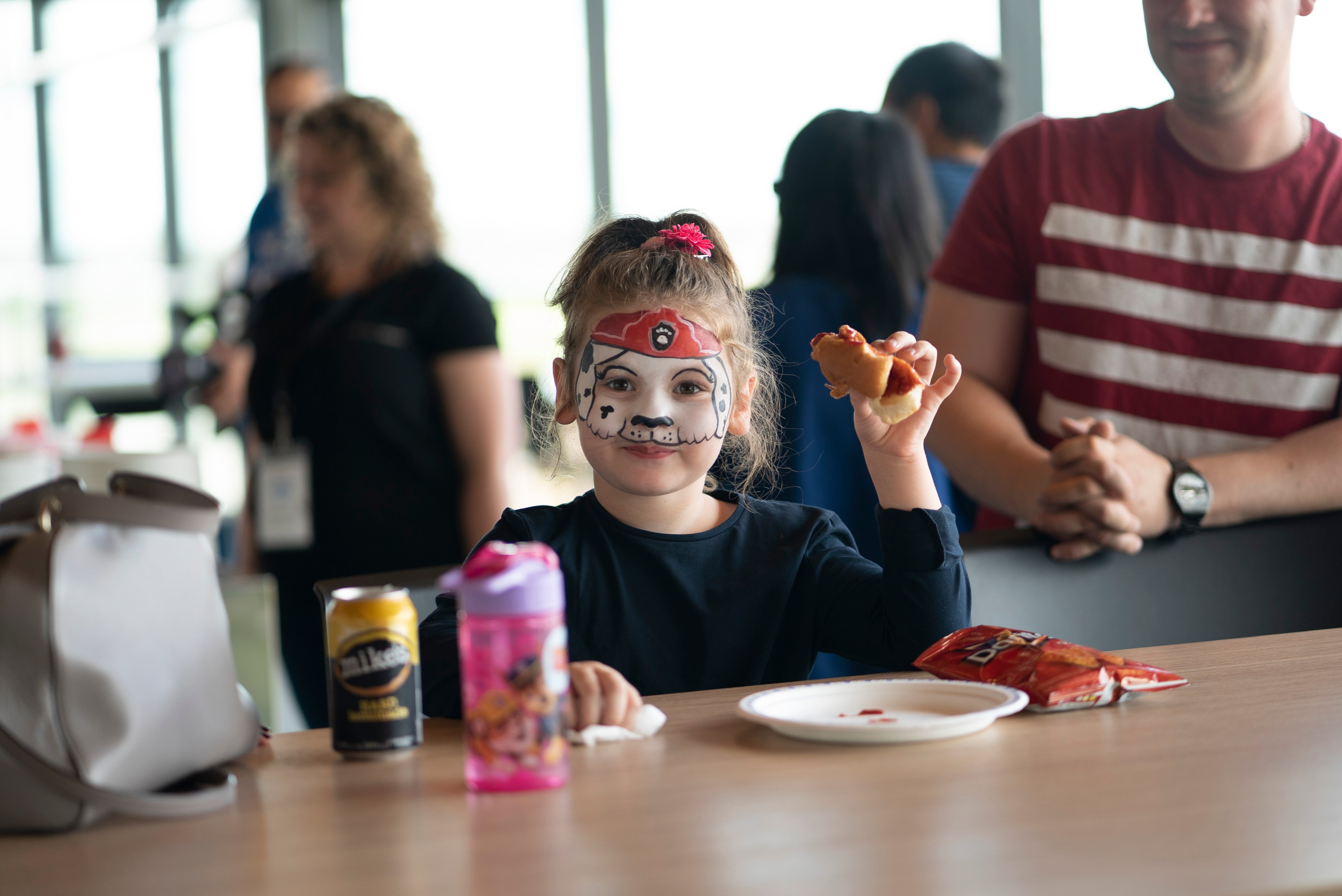 A young girl enjoys a hotdog and chips at Bold Friends & Family Day